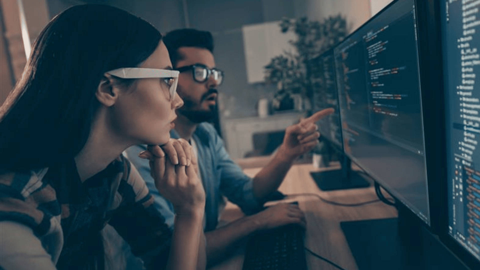 two business people watch together and indicate monitor testing